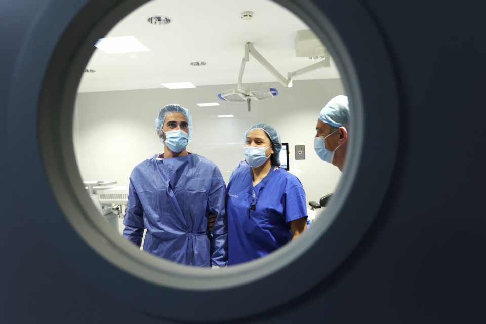 Un paciente junto a una doctora saliendo de un quirófano después de una intervención quirúrgica